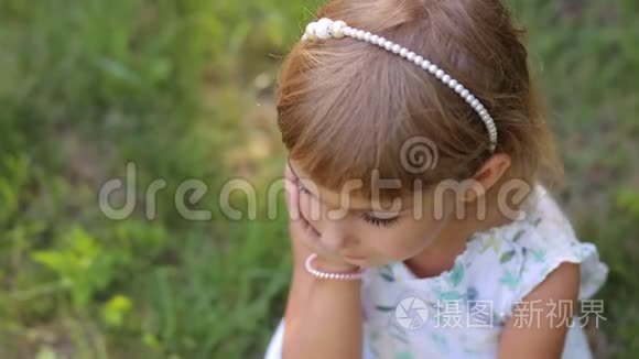 绿色草地背景下公园里微笑的小女孩的肖像。 异色差