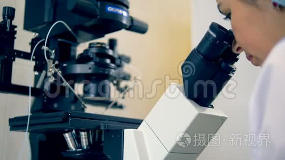一位女科学家正在近距离观察显微镜