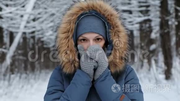在冬天的森林里,特写的女人用呼吸温暖她的双手.短视频