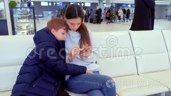 女士带着儿子在机场大厅的手机上在线登记。