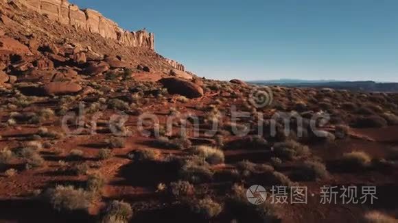 无人机在巨大的山脉附近低空飞行，亚利桑那州的砂岩景观覆盖着岩石和阳光明媚的天空。