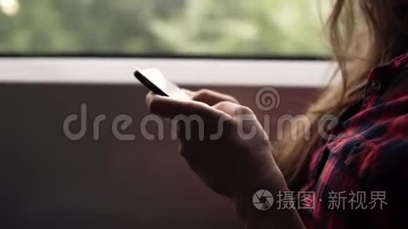 用手机`女人的双手极其亲密。 休闲格子衬衫.. 漂亮的女孩坐火车旅行。 大自然