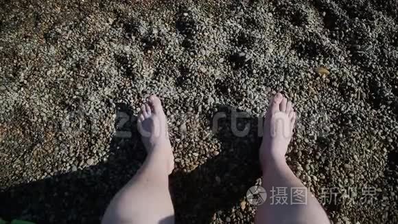 夏季概念女性在鹅卵石海滩上的双腿，而女性则在皮肤上涂防晒霜
