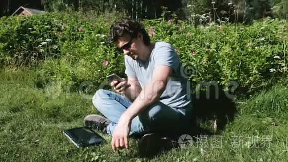 在阳光明媚的日子里，坐在公园里的人正在用手机打字。 自由职业。