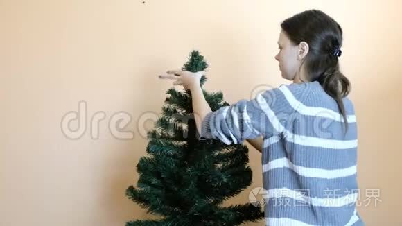 女人把树枝连接到人造树的顶端。 在圣诞节之后。