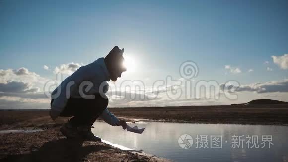 可爱的女孩在日落时在湖边玩纸船。 童梦和旅行理念，生活方式..