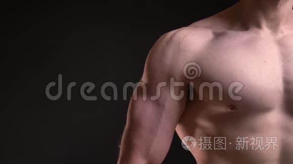 黑色背景下男性肌肉二头肌和乳房的特写肖像。