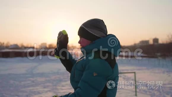 冬公园里的一个少年微笑着挥手致意.. 日落的时候。 在新鲜空气中游走。 健康的生活方式