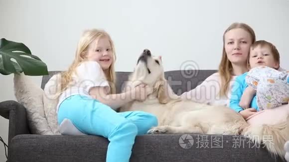 家庭宠物的生活。 妈妈，儿子和女儿正和一只金毛猎犬在客厅的沙发上休息