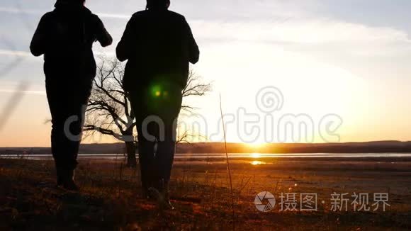 两个朋友夕阳西下往前走，探险旅行的概念，肩上背着一个背包