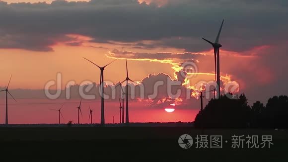 风力涡轮机在日落时在田野里旋转。