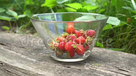 在绿色背景的英国老花园里，用新鲜的有机草莓将玻璃碗合上