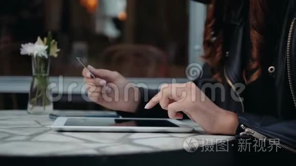 年轻女子拿着信用卡，用笔记本电脑。 现代咖啡馆的网上购物理念