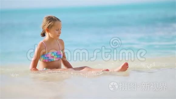 可爱的小女孩坐在雪白的沙滩上视频