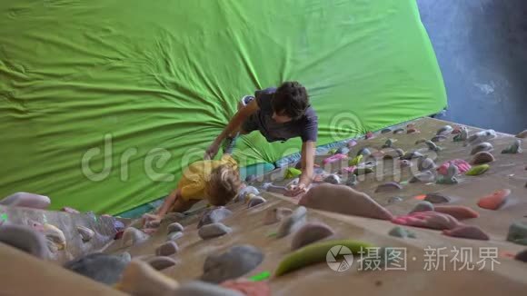 一个年轻的攀岩教练教小男孩如何在一个巨石攀岩馆里爬墙