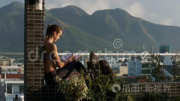 女孩坐在盆栽的露台墙上打电话视频