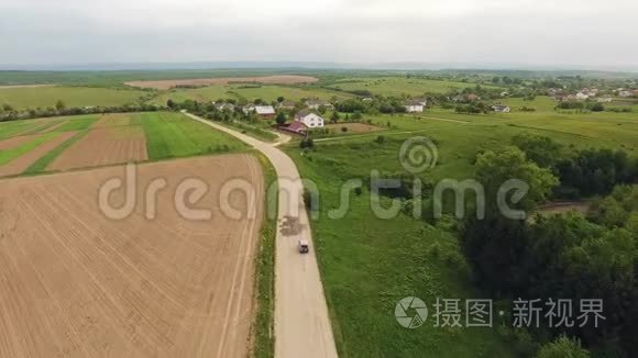 空中：森林中的乡间小路上白色汽车行驶的景色.. 无人驾驶飞机在松树的碎石路上飞行