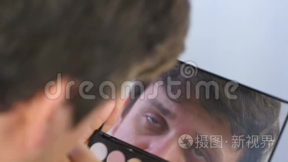 年轻人用镊子在家里的镜子前拔掉眉毛。