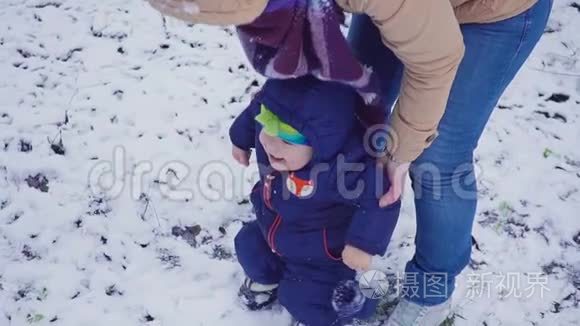 快乐的一岁男孩和他的母亲在冬天的森林里玩耍。