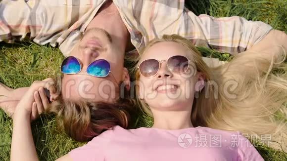 快乐的年轻夫妇享受周末，躺在草坪上聊天，夏天