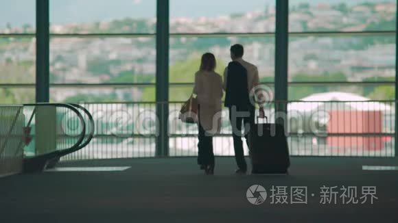 商务旅行，男人和女人步行到机场的自动扶梯，携带行李