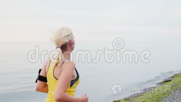 stadicam年轻女子在海或湖的背景下慢跑，后景。 侧视图