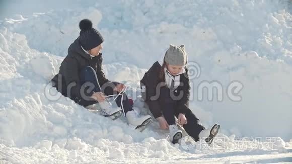 女孩们穿着溜冰鞋坐在靠近溜冰场的雪堆里，收紧鞋带，动作缓慢