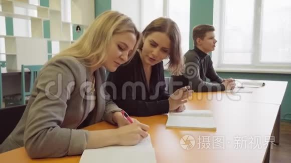 女学生在笔记本上写字，并向她的朋友解释一个教训