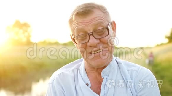 无忧无虑的退休男子微笑着看着相机。 一位戴眼镜的老人的肖像。 节日快乐。 父亲节