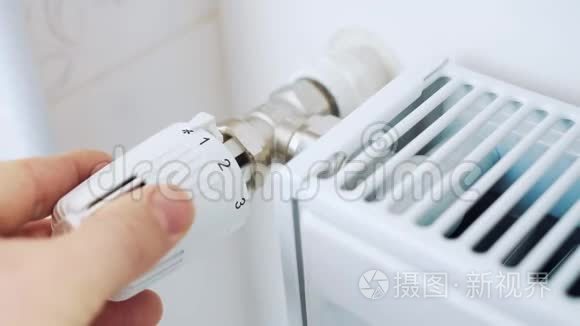 一个男人用暖气片上的恒温器调节房子的温度