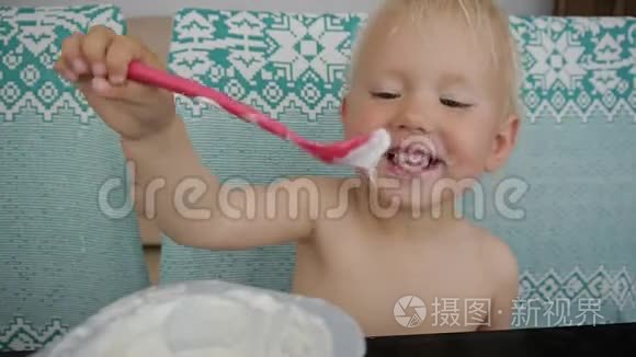 宝宝吃酸奶弄得一团糟。 笑起来的蓝眼睛小女孩吃酸奶。