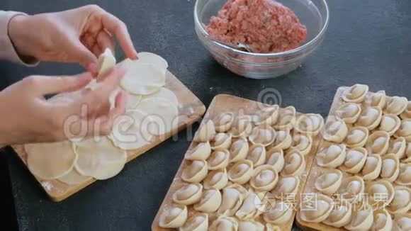 女人用肉馅包饺子，特写的手。 上景。