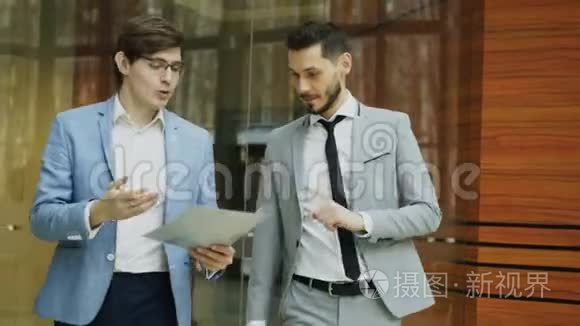 两位商人同事在现代办公大厅里散步和讨论文件