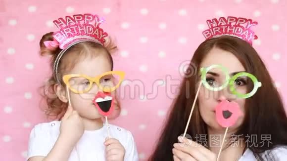 幸福的家庭母亲和女儿穿着眼镜和嘴唇和不同的装饰来庆祝生日。 这就是