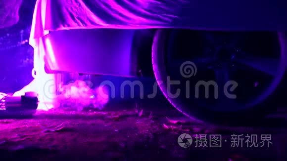 站在废弃房子里的烟雾中，被布料覆盖的汽车用紫色照明。