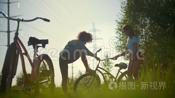 一个年轻的骑自行车的人弯着腿，背景是女孩在喝水