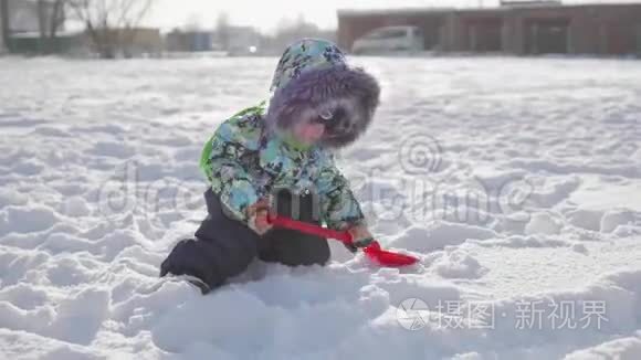 一个小孩在冬天的公园里玩雪.. 阳光明媚的冬天白天。 新鲜空气中的乐趣和游戏。