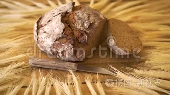 木制桌子上有葵花籽和木刀和黑麦耳朵的深色自制面包