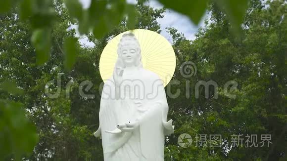 佛寺中的佛像妻子，背景是绿色的植物和树木。古代佛教宗教雕塑
