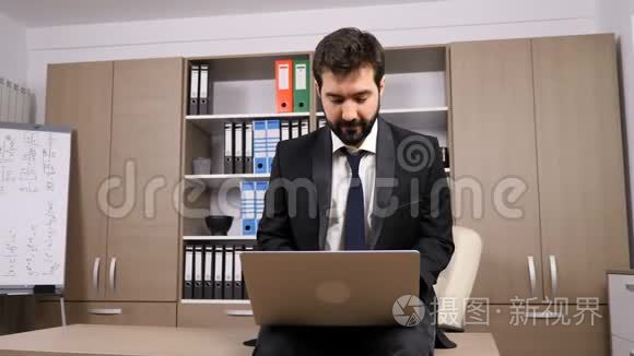 格式的商人坐在桌子上，在笔记本电脑上打字