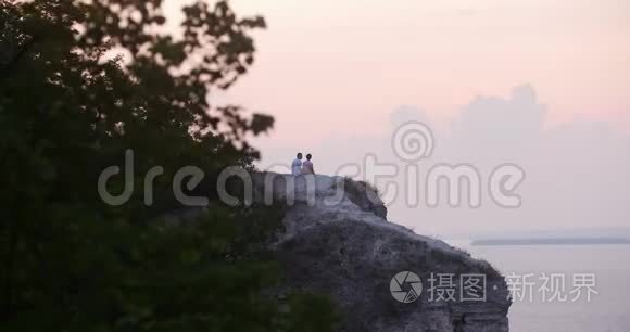 坐在山上欣赏日落的年轻男女