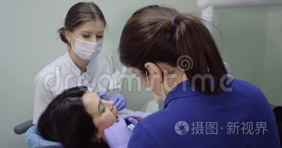 牙医为一位年轻女性做检查和牙科清洁，护士坐在旁边帮助，病人快乐，微笑