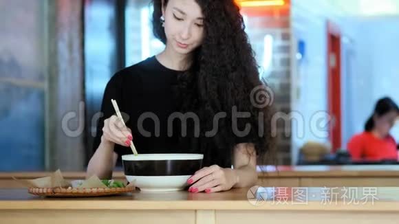 一个可爱的年轻亚洲女孩在亚洲咖啡馆里拍了一张pho汤的照片。 中国、越南或日本咖啡馆或餐馆