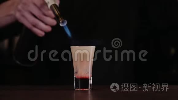 酒保做了一杯火鸡尾酒。 广岛鸡尾酒。 酒吧老板点燃了酒吧里的打火机