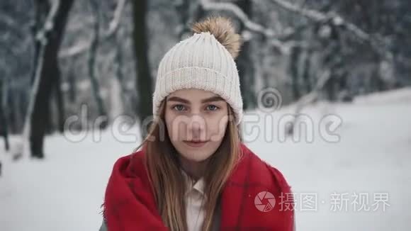 年轻漂亮的女孩穿着温暖的衣服走在圣诞树附近，看着相机。 穿着