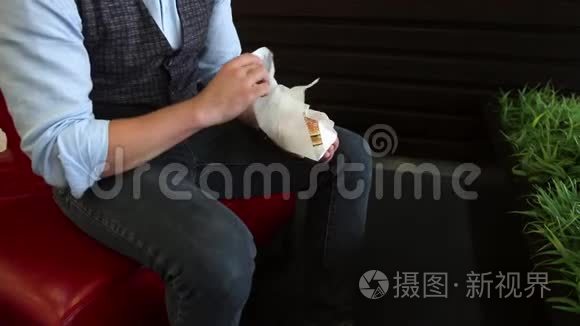 一个男人坐在咖啡馆里打开三明治