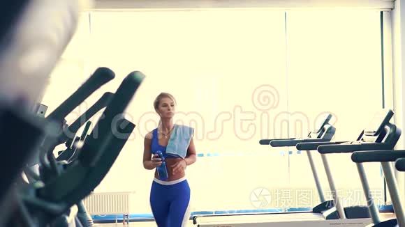 经过艰苦的训练，女运动员从蓝色的塑料瓶中喝水