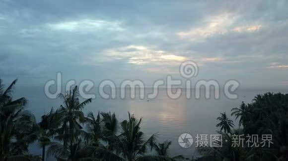 在印度尼西亚巴厘岛，通过海滩上的棕榈树，从太阳从海面升起的无人机上看到空中景色