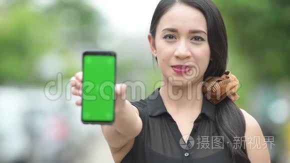 年轻快乐美丽的亚洲女商人在户外街头展示电话