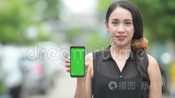 年轻快乐美丽的亚洲女商人在户外街头展示电话